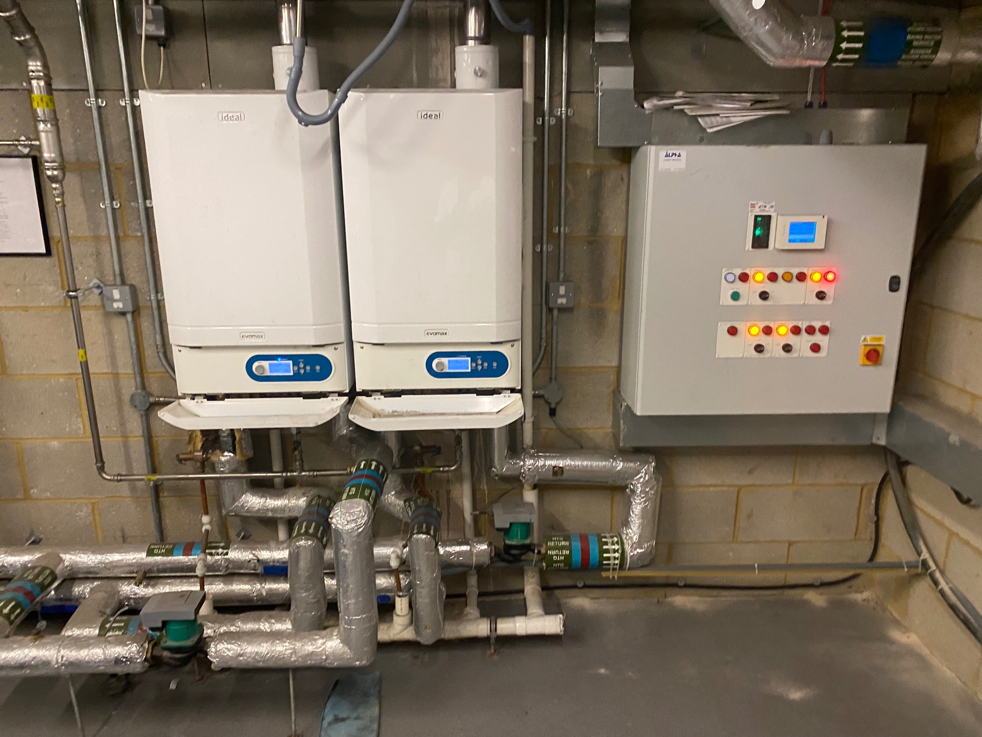 Twin Ideal Evomax wall-hung commercial boilers installed in London plant room with cascade header, insulated LTHW flow and return pipework and Alpha control panel